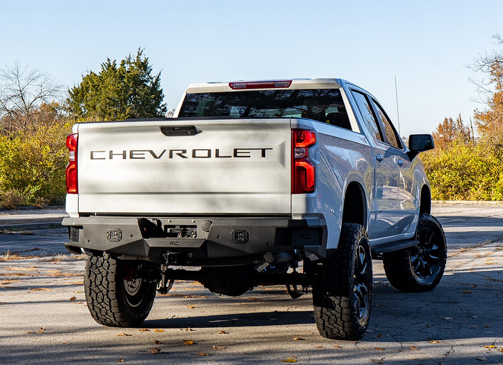 Rear angle view of a white lifted 2022 Chevy Silverado with accessories installed.