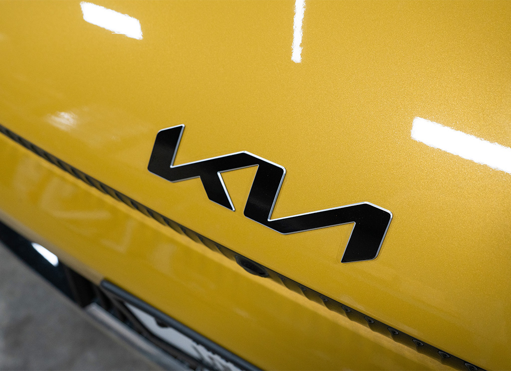 Blackout Kia emblem overlay on a yellow Kia EV6