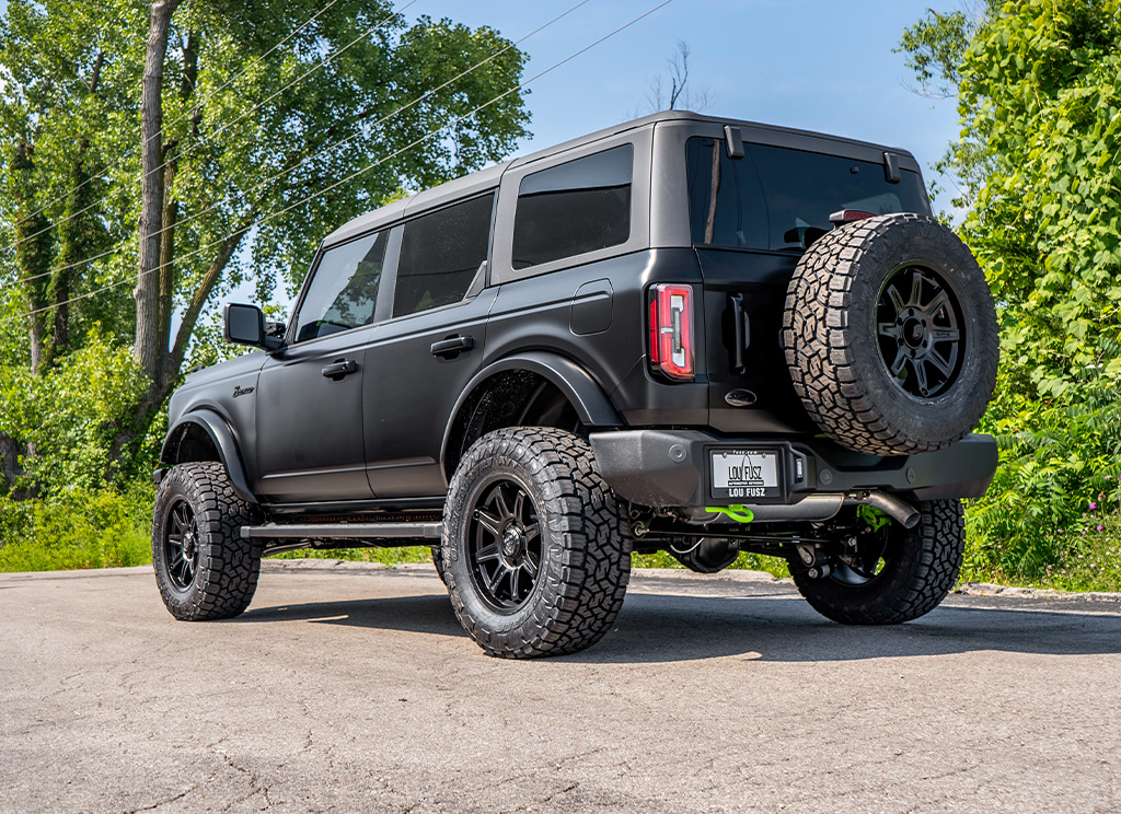 Rear angle view of a custom satin black wrapped 2023 Ford Bronco with green accents.