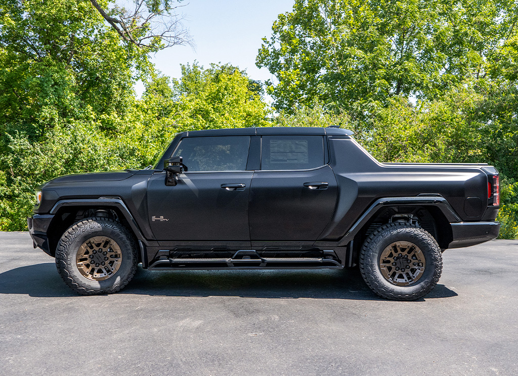 Profile view of a custom satin black Hummer EV truck with bronze powder coat wheels.