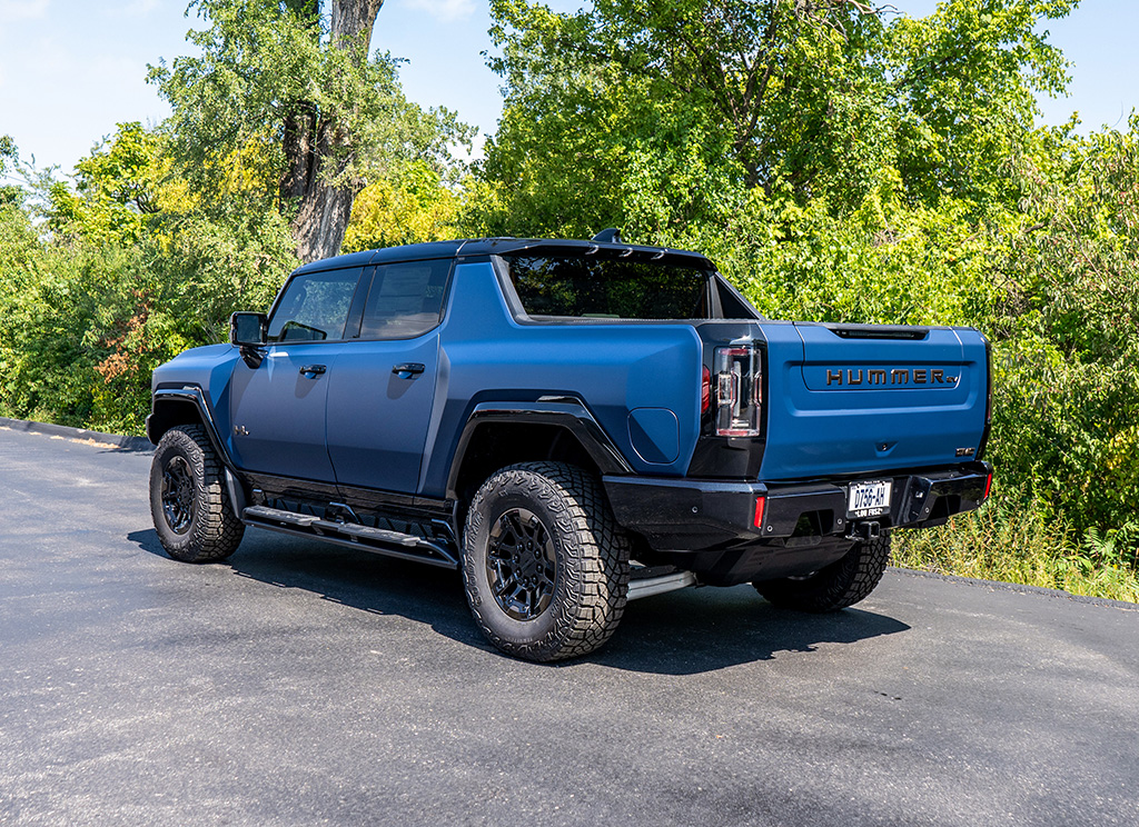 Rear angle view of a 2024 Hummer EV truck wrapped in a satin blue vinyl.