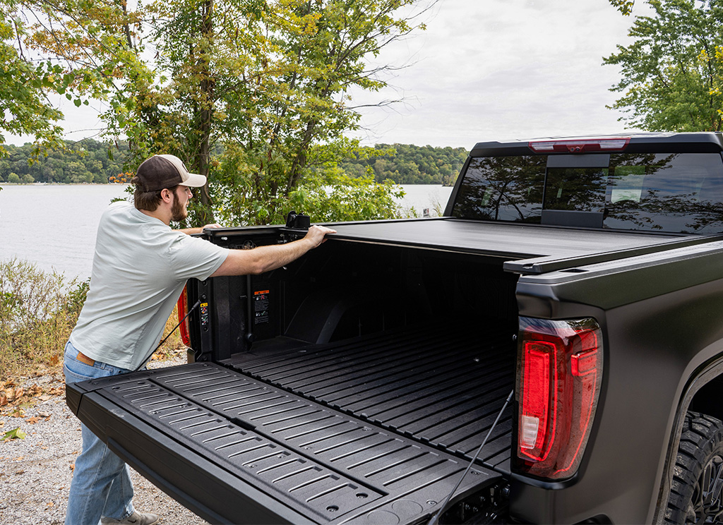 Low profile retractable tonneau cover on the bed of a custom GMC Sierra Pickup truck.