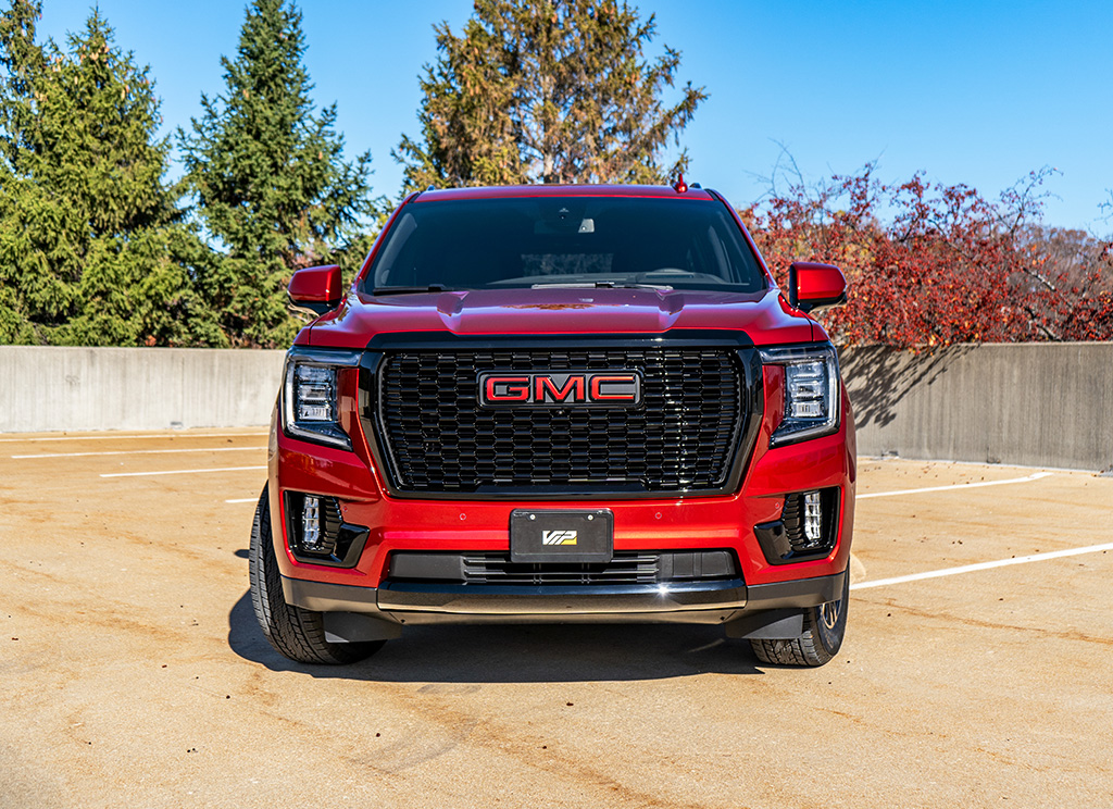 Front end of a custom red GMC Yukon Denali with a blackout grille.