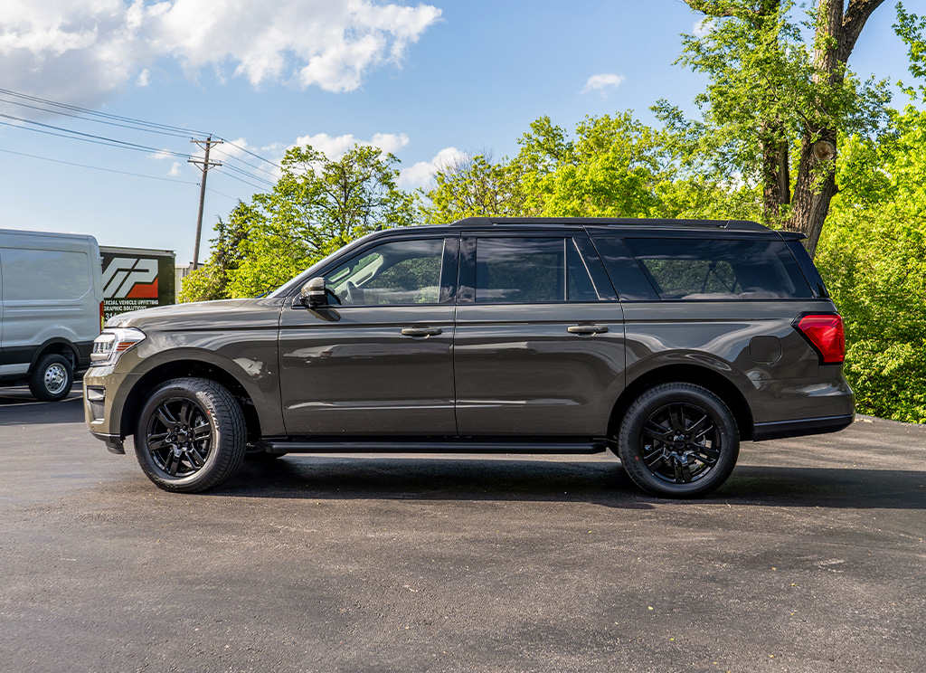 Side profile of a Wild Green 2024 Ford Expedition with black trim and a two-tone vinyl roof wrap.