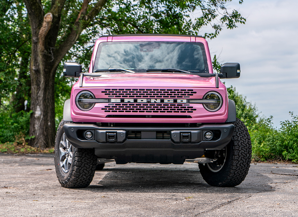 front view of the Ford Bronco with a custom pink grille and white Bronco nameplate lettering.