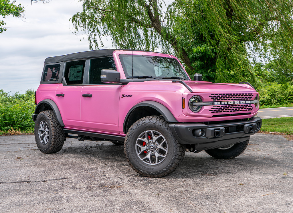 Full view of a custom pink Ford Bronco with a full vinyl wrap and window tint.