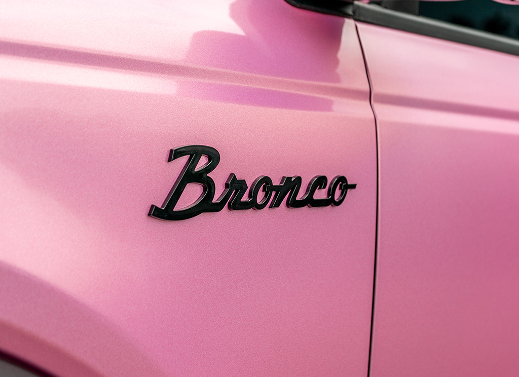 Black Bronco vintage script emblem against a pink vinyl wrap.