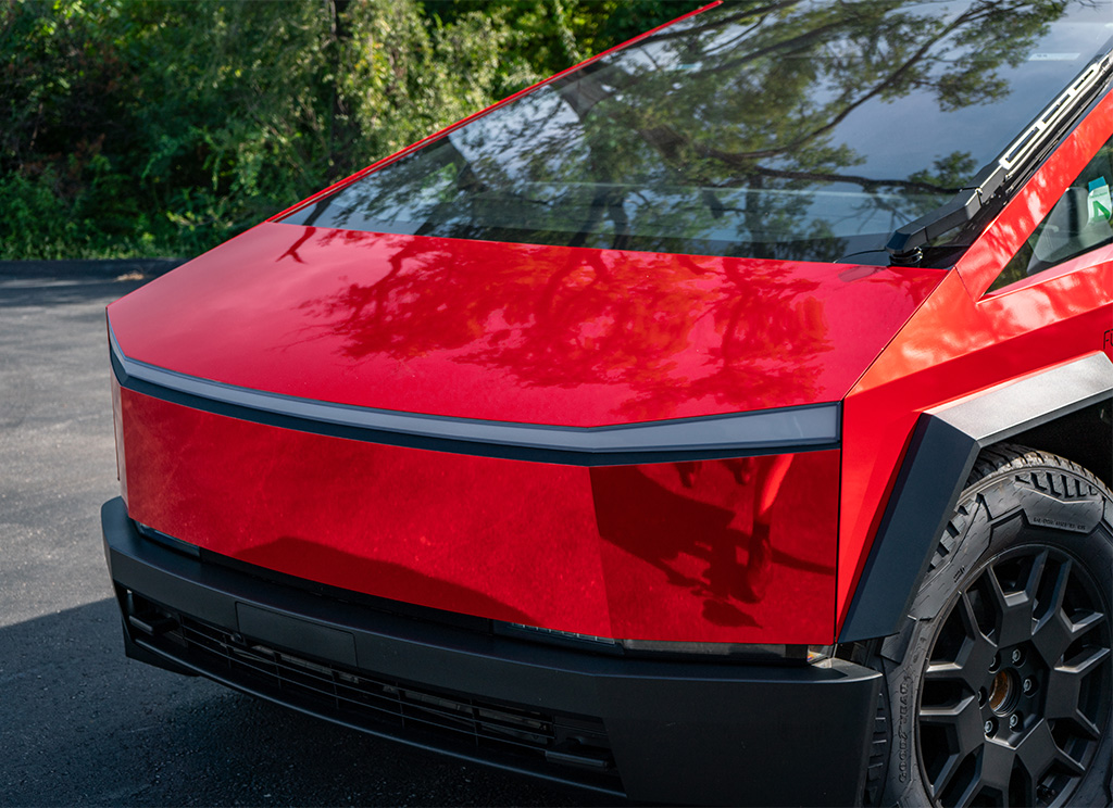 Close-up of the super chrome gloss red vinyl wrap on the front of the Cybertruck.