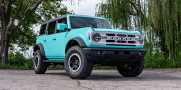 Custom teal blue Ford Bronco with a white grille and emblems.