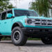 Custom teal blue Ford Bronco with a white grille and emblems.
