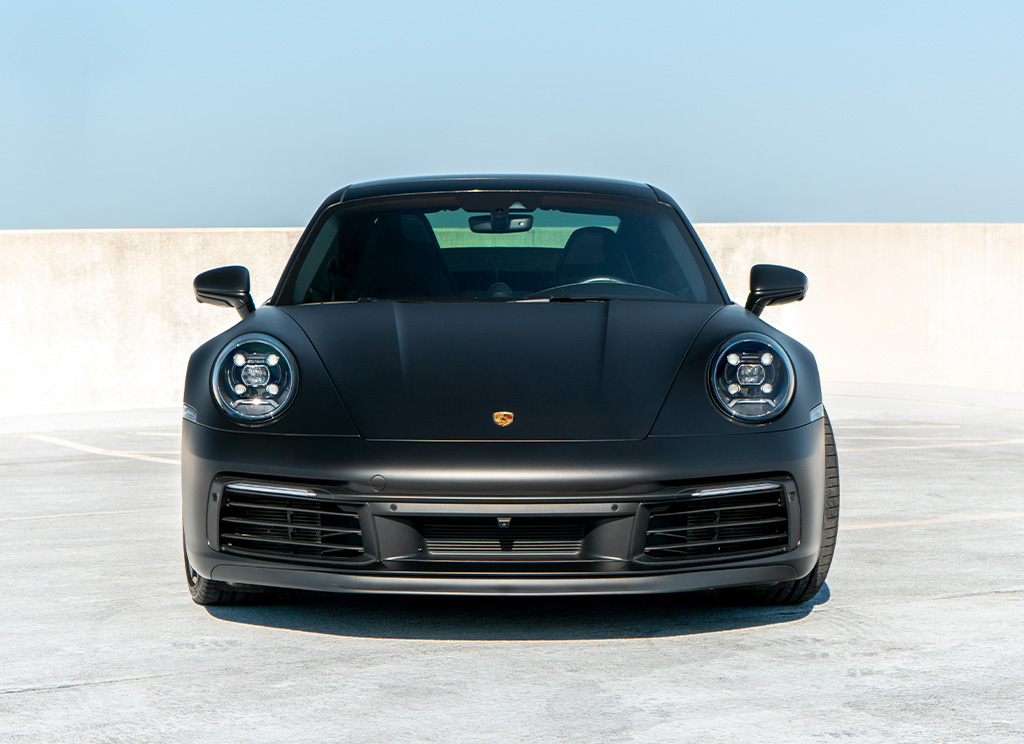 Front end view of a matte black Porsche 911.