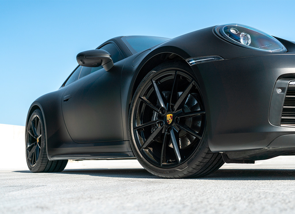 Close-up of Black Porsche 911 wheels and a matte black wrap vinyl wrap.