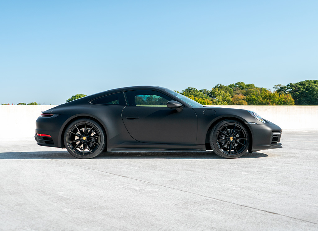 Side profile view of a custom Porsche 911 with a matte black vinyl wrap.