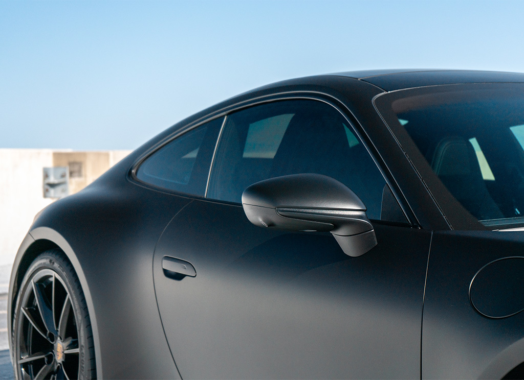 Tinted front windows on a matte black Porsche 911.