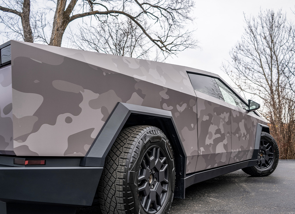 Close up of a gray camouflage printed vinyl wrap on a Tesla Cybertrucks rear fender.