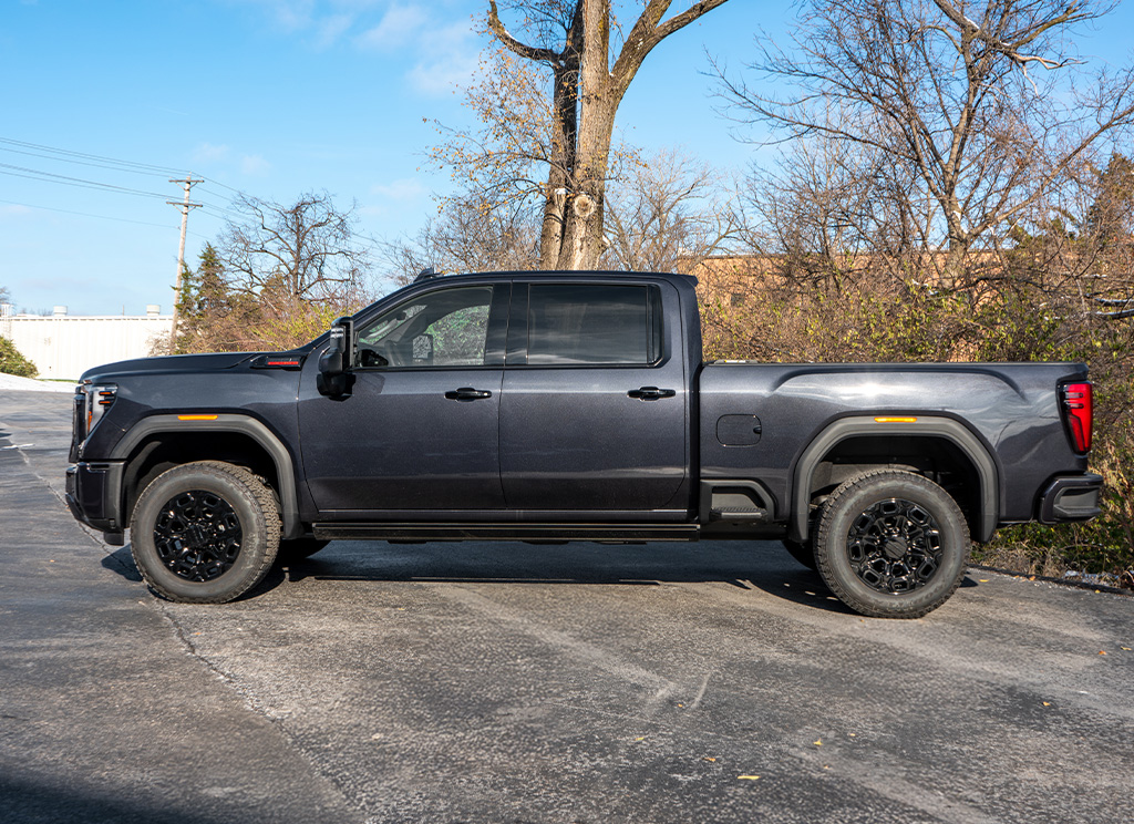 Side profile of a 2024 GMC Sierra HD 3500 with chrome delete trim and black powder coated wheels.