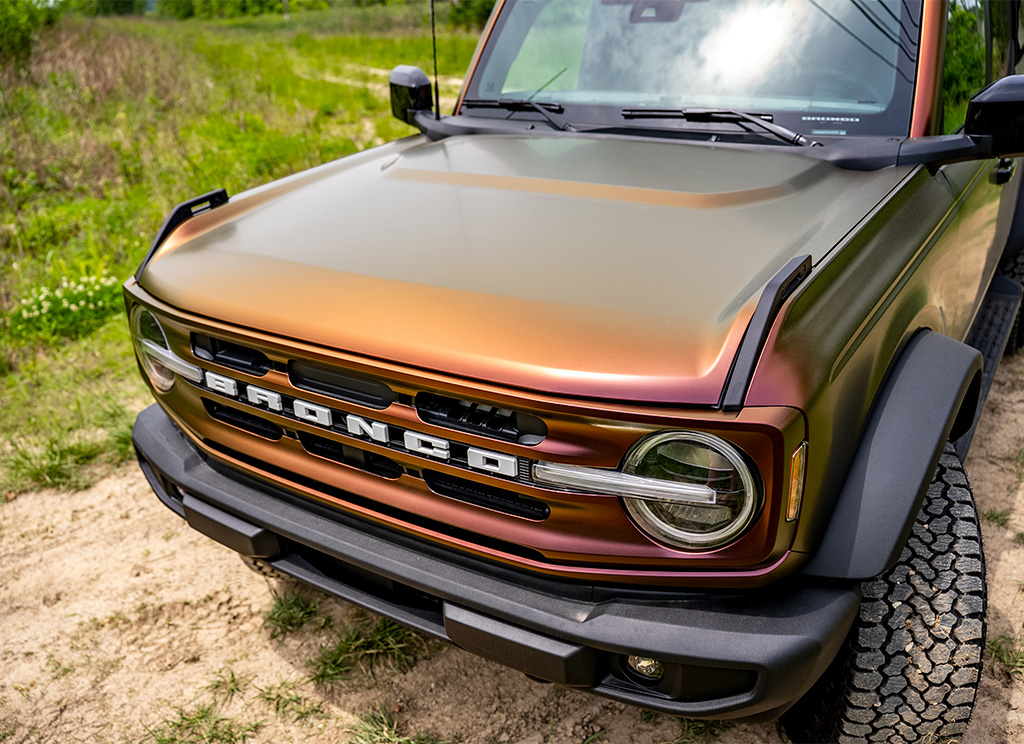Hood and grille of a Ford Bronco that has a volcanic Flare color flip vinyl wrap.