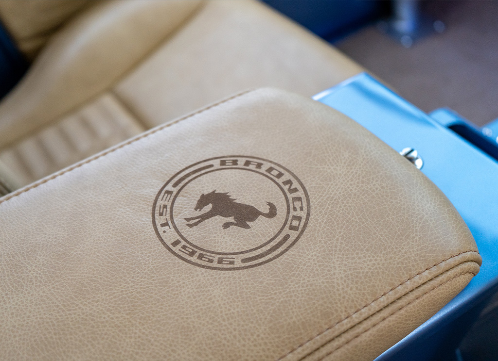Close-up of custom laser engraved Bronco branding on the center counsel arm rest of a restored 1971 Ford Bronco