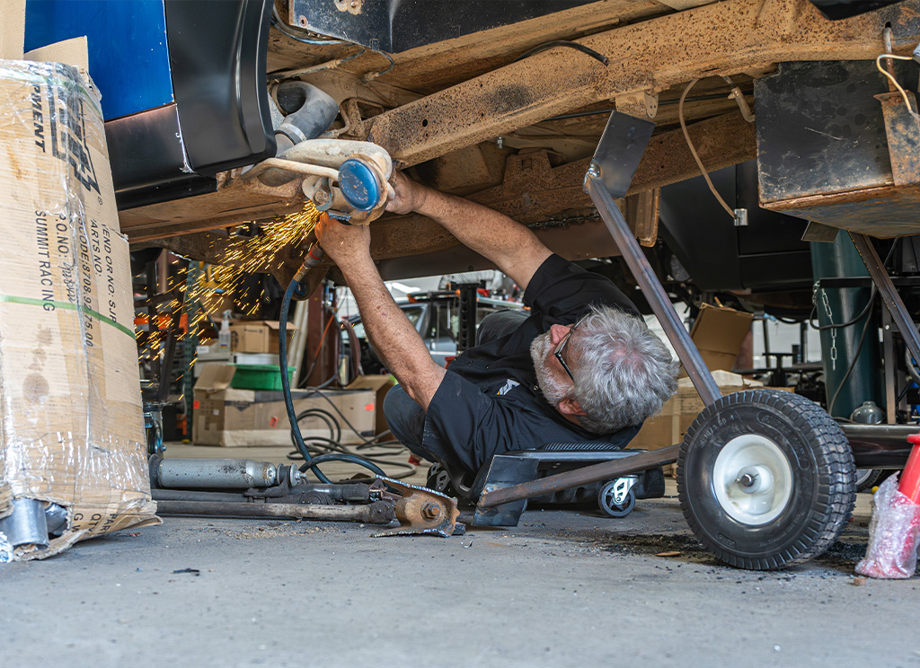 Restoration technician cutting rusted parts off the chassis.