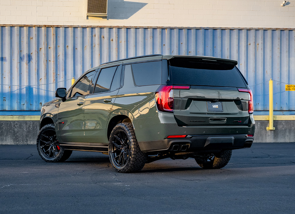 2026 GMC Yukon AT4 rear angle view with blackout trim and custom wheels.