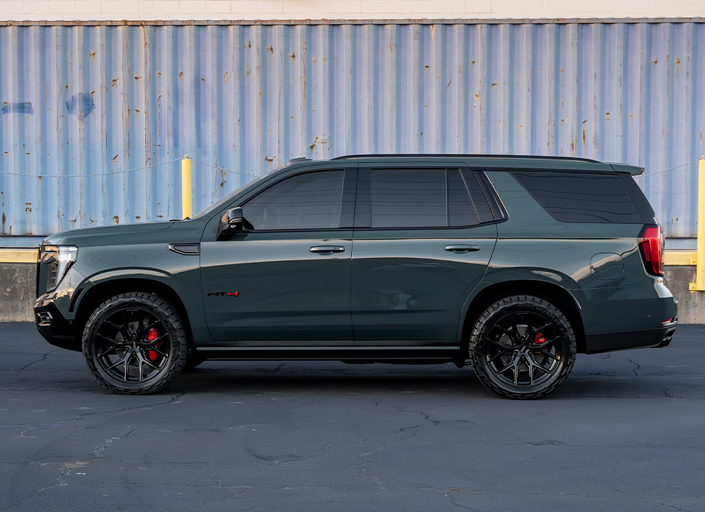 Side profile of a Midnight Pine 2026 GMC Yukon AT4 with custom blackout trim and wheels.