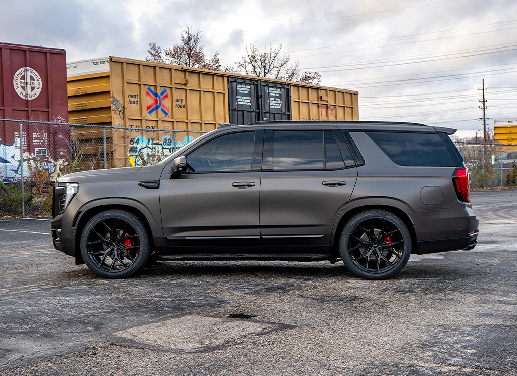 Side profile of a satin gray 2026 GMC Yukon Denali with custom chrome delete trim and wheels.