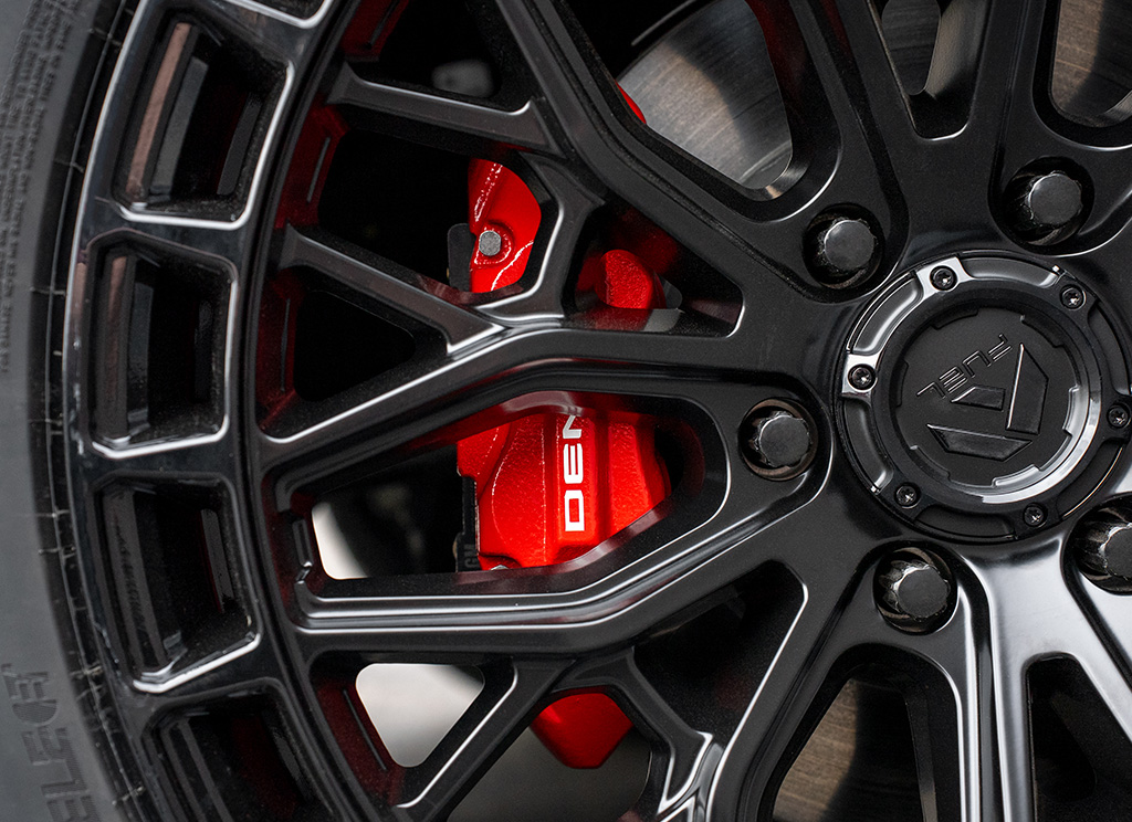 Red painted brake calipers with white Denali lettering behind black wheels.