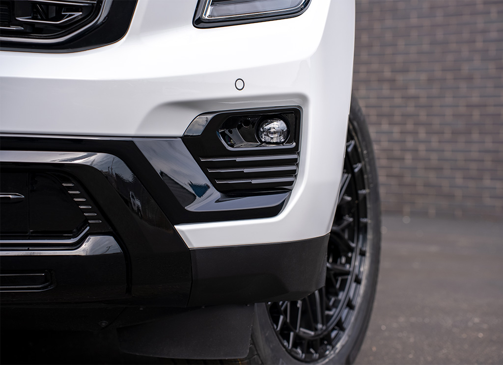 Close-up of a custom black fog light bezel molding on a white 2026 GMC Yukon Denali.