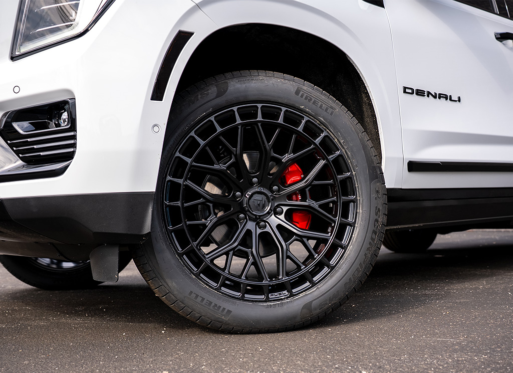White 2026 GMC Yukon Denali with gloss black Fuel Sigma wheels and red brake calipers.