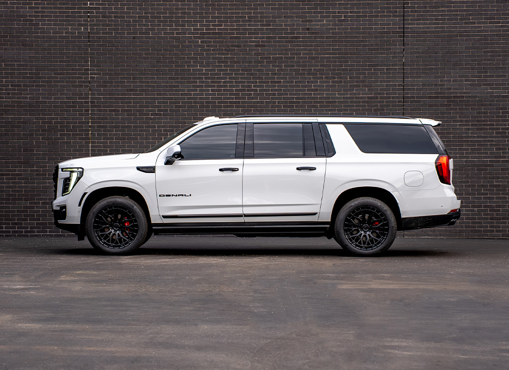 Side profile of a Summit White 2026 GMC Yukon Denali with black chrome delete trim.