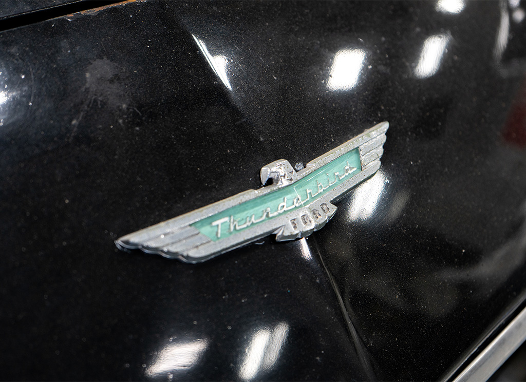 Old 1956 Ford Thunderbird emblem on original black paintjob.