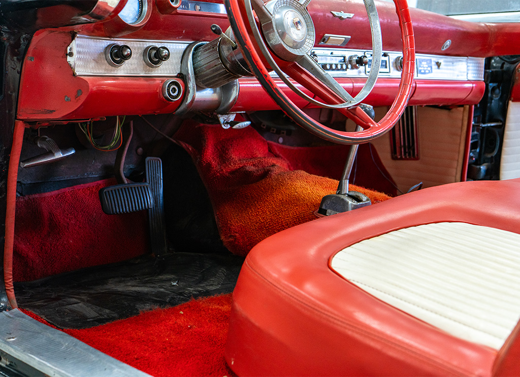 Old worn out red carpeting in a 1956 Ford Thunderbird before getting replaced