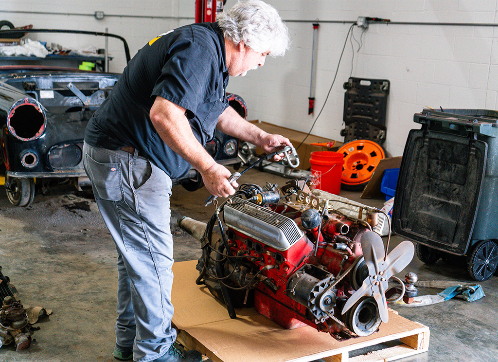 Technicians removing the old 1956 Ford Thunderbird engine and transmission.