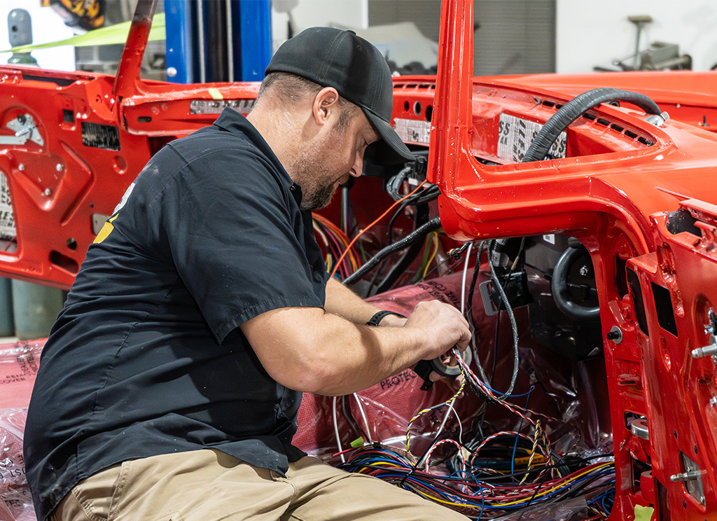 Automotive restoration technician rewiring the interior of a 1956 Ford Thunderbird dashboard.