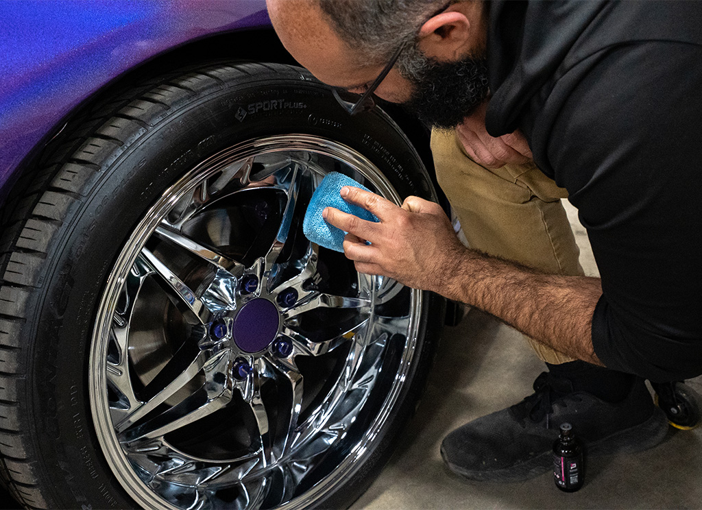 Technician installing ceramic coating on shiny chrome rims of a 1991 Nissan 300ZX.