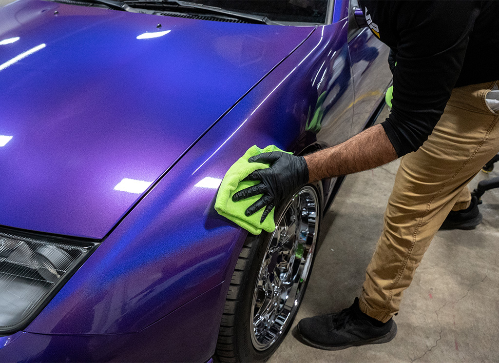Close-up of a technician installing ceramic coating on a purple 1991 Nissan 300ZX.