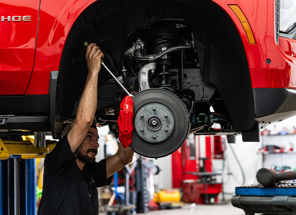 Technician installing red painted calipers on 2026 Chevy Tahoe. 