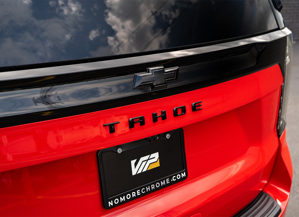 Black Tahoe Nameplate and blackout Chevrolet bowtie emblem on the tailgate of a red 2026 Tahoe.
