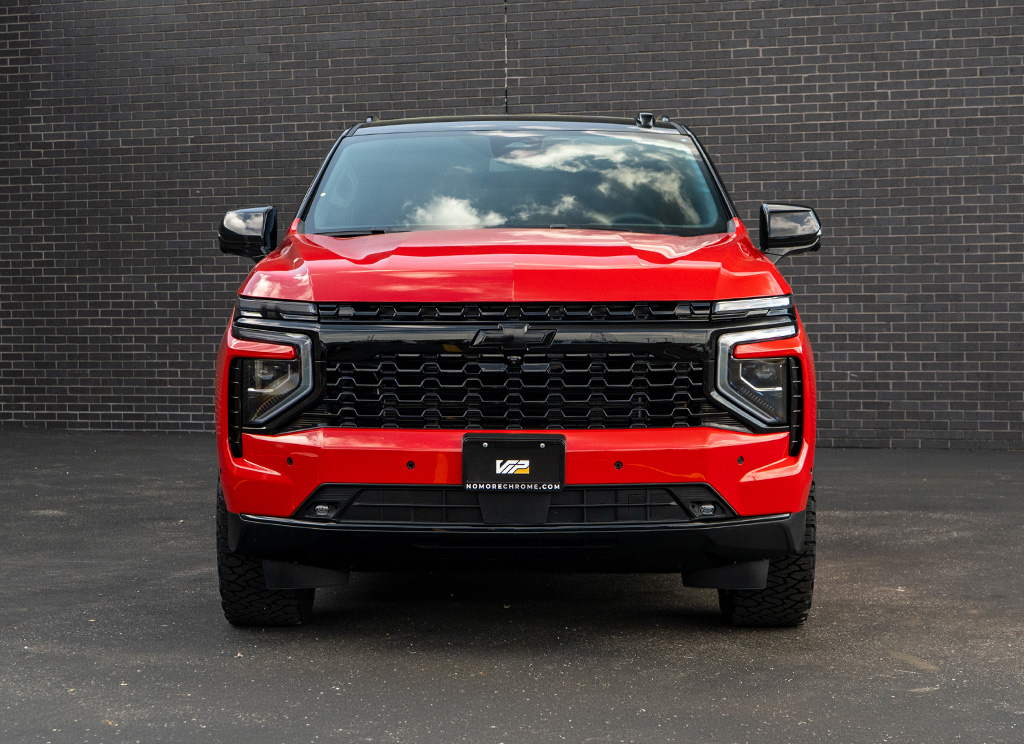 Front-end of a red 2026 Chevy Tahoe with a blackout High Country grille.
