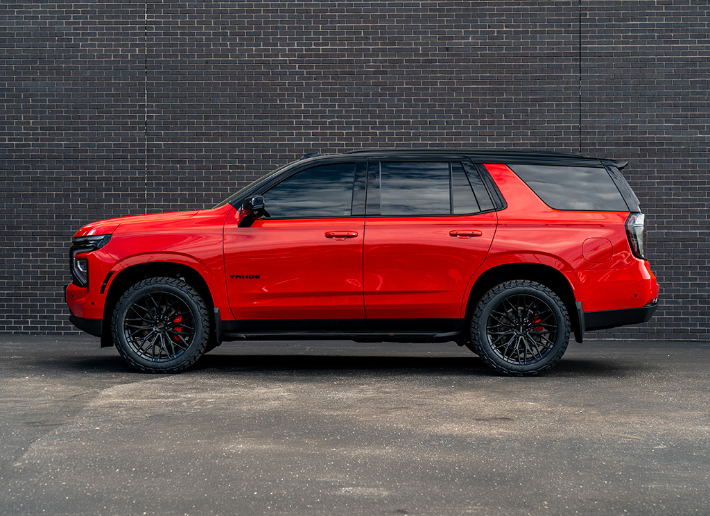 Side profile of a custom Victory Red 2026 Chevy Tahoe with black chrome delete accessories.