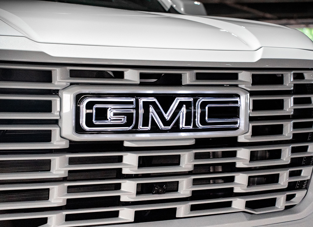 Close-up of a color-matched White Frost 2026 GMC Yukon Denali grille with a light-up LED GMC Emblem.